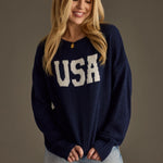 Woman wearing a navy blue sweater with 'USA' text on a plain background